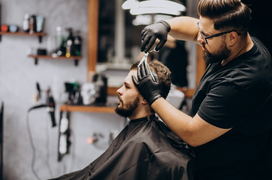 A focused barber in black gloves shapes a client's hair with precision in a well-equipped salon.