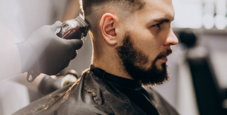 Client doing hair cut at a barber shop salon, hands with the trimmer in black gloves