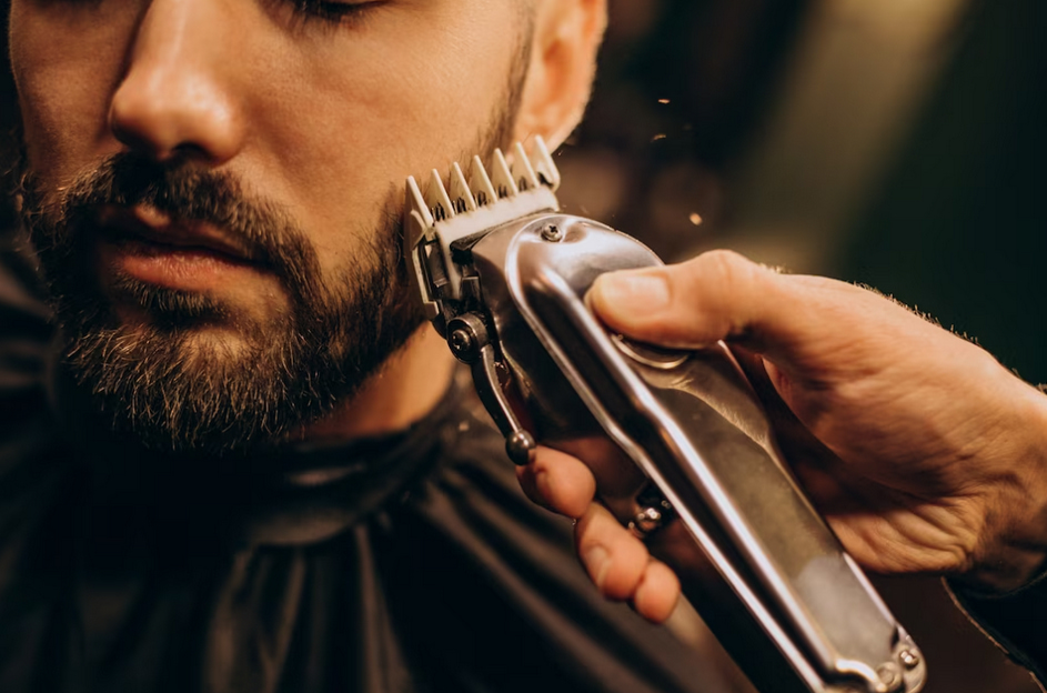 a close up view of hand trimming the beard of a man