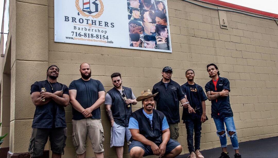 Group of hairdressers against a wall with a poster