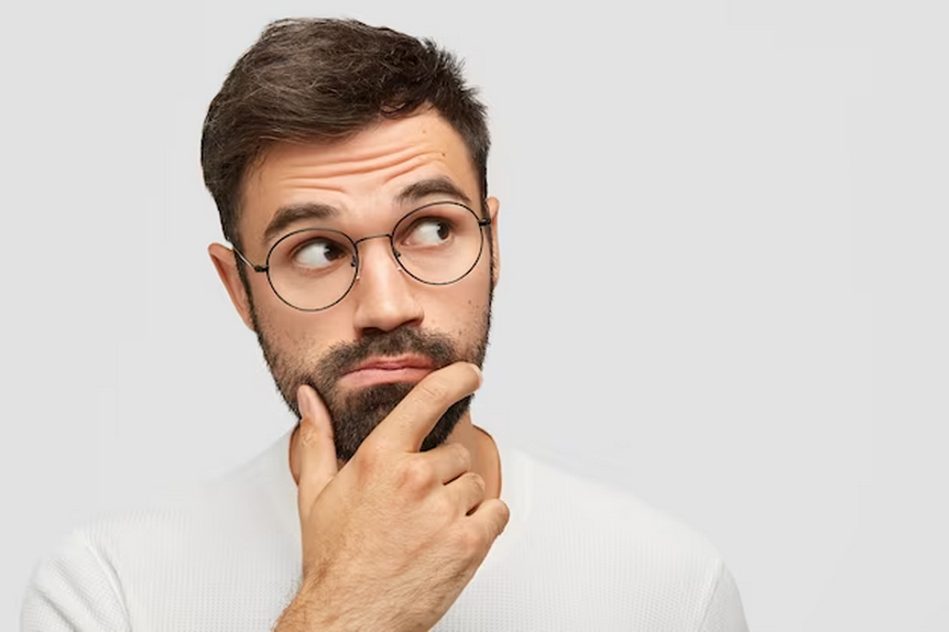 Bearded man in glasses glancing sideways while touching his chin