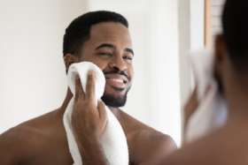 Man using towel in front of a mirror.